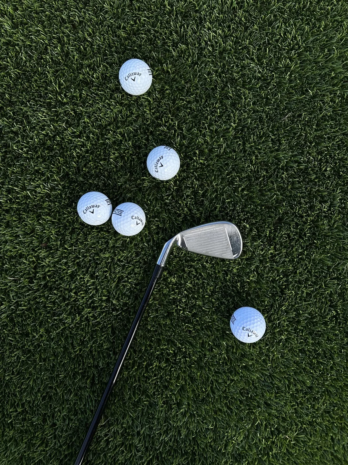 Golf irons and practice balls resting on turf